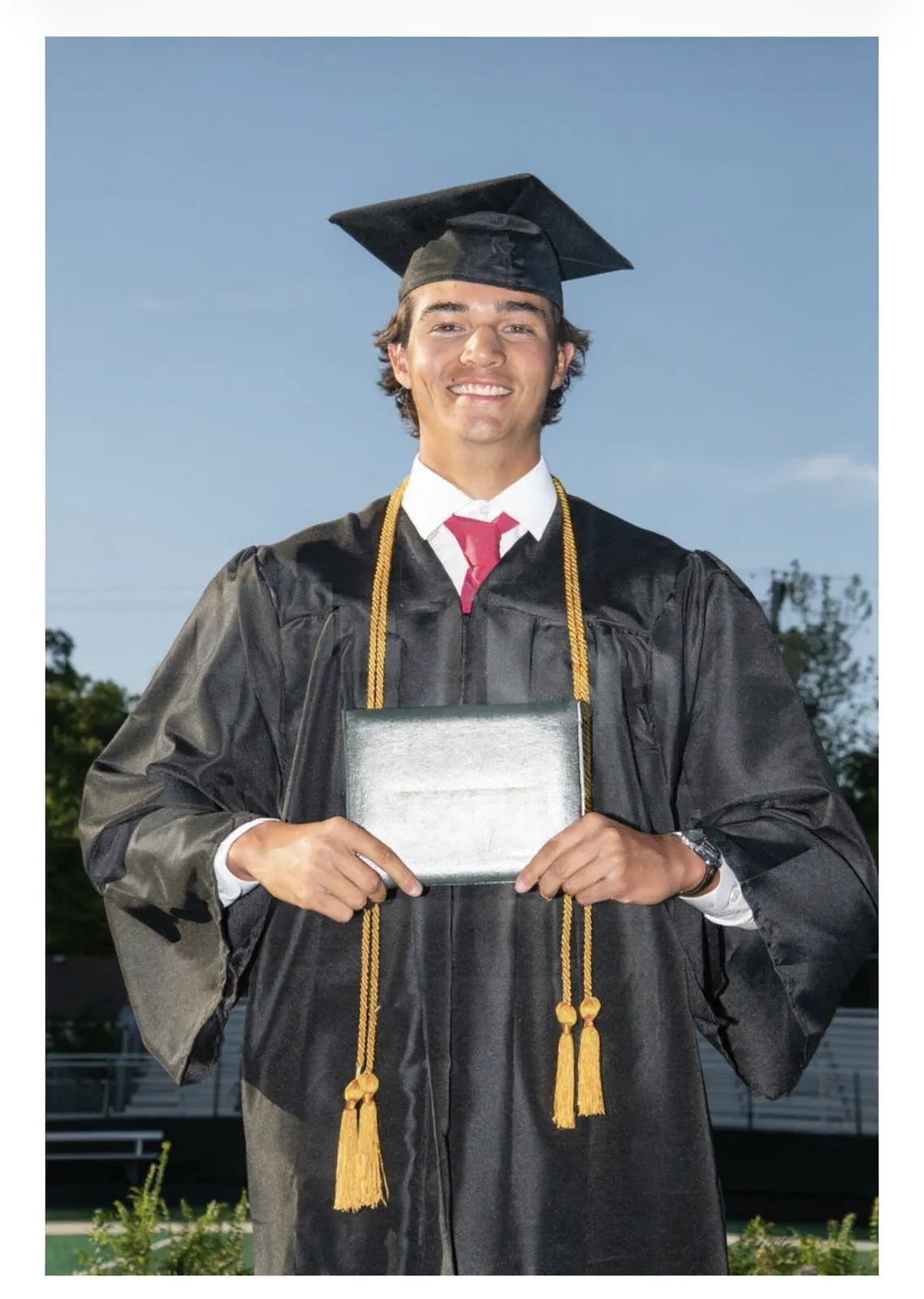 Avi Hanusz in cap and gown with his Ottawa Hills High School diploma
